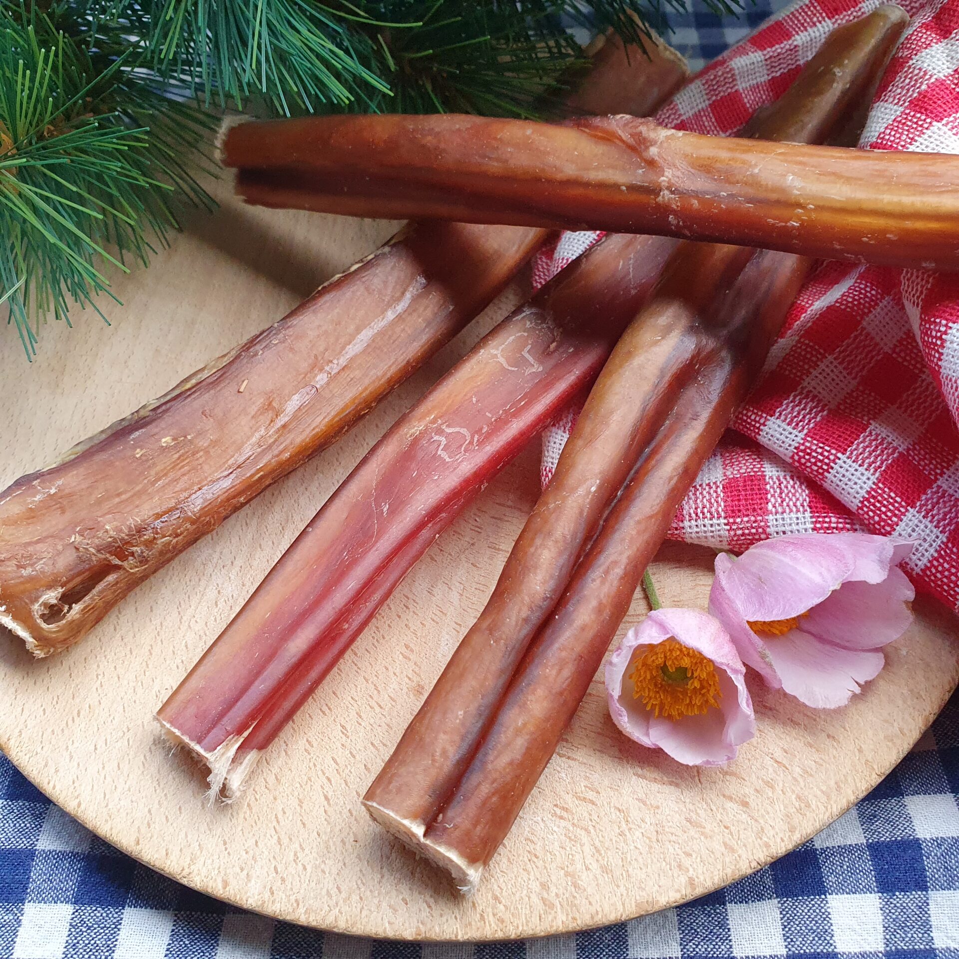 Ochsenziemer – naturgetrockneter Kauartikel für Hunde Ochsenziemer als getrockneter, naturbelassener Kauartikel für Hunde, ruhig auf Holzbrett platziert.