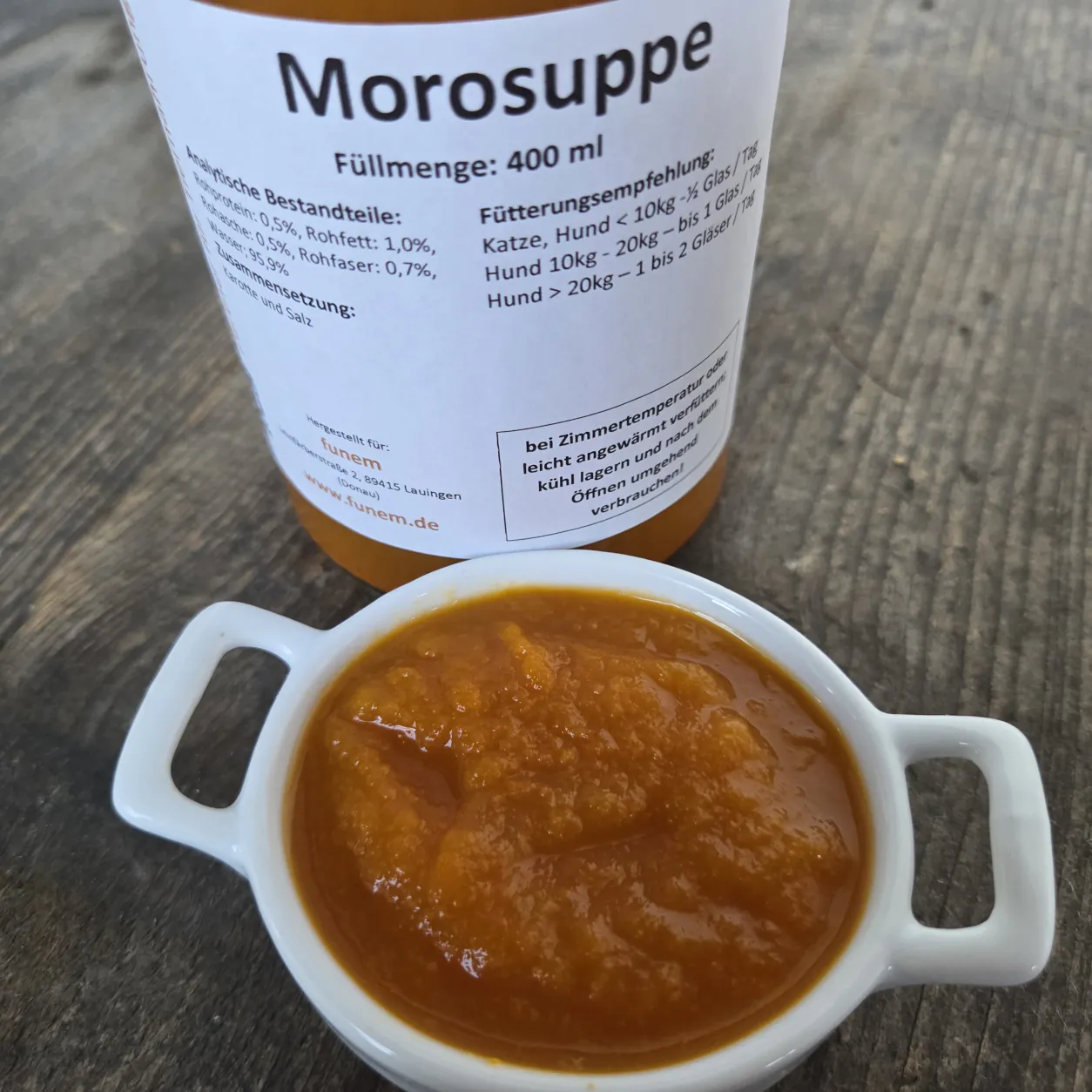 Morosuppe für Hunde und Katzen serviert in einer Schüssel mit Produktglas im Hintergrund