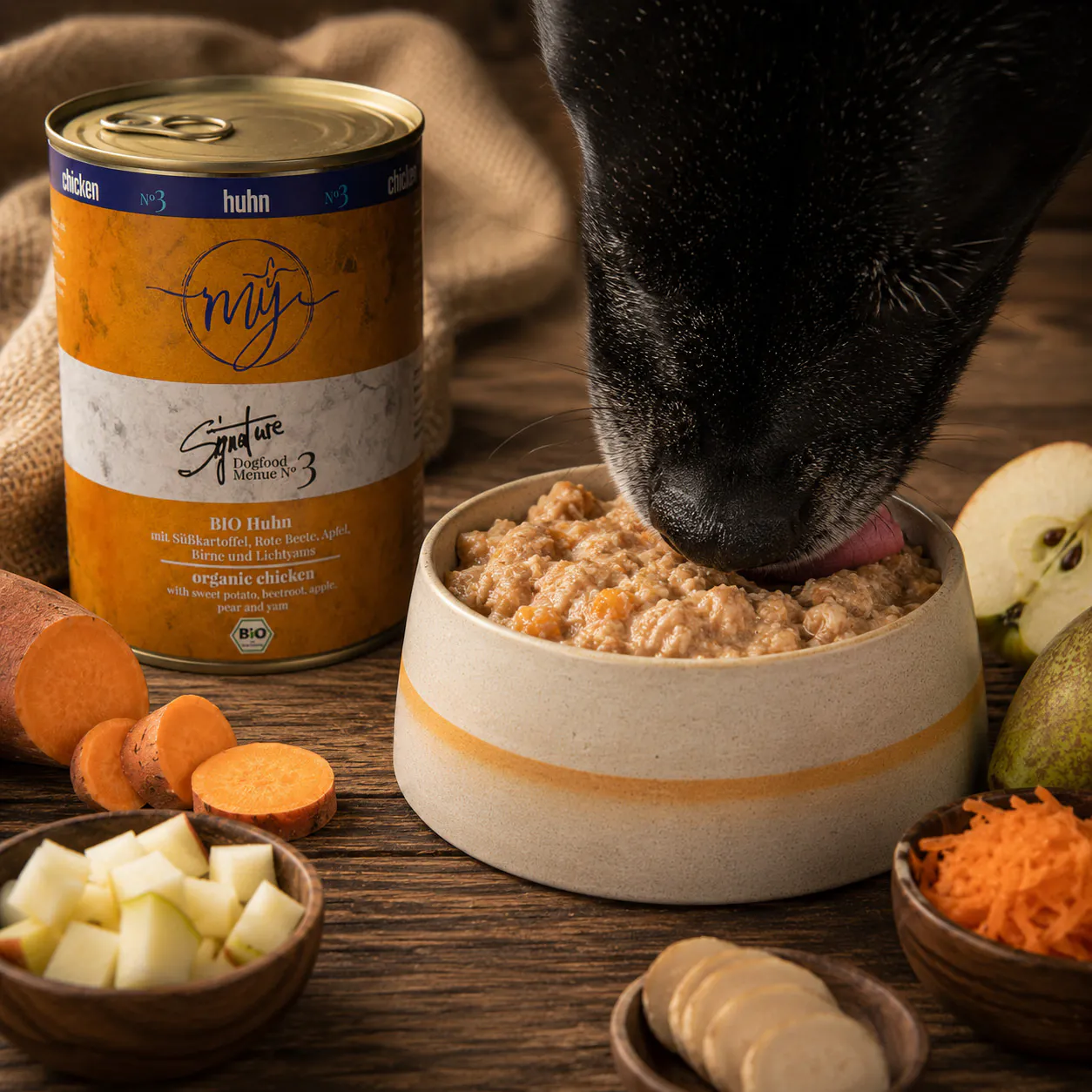 Hund frisst Nassfutter aus einem Napf neben der Dose mÿ Signature Menü No. 3 Huhn