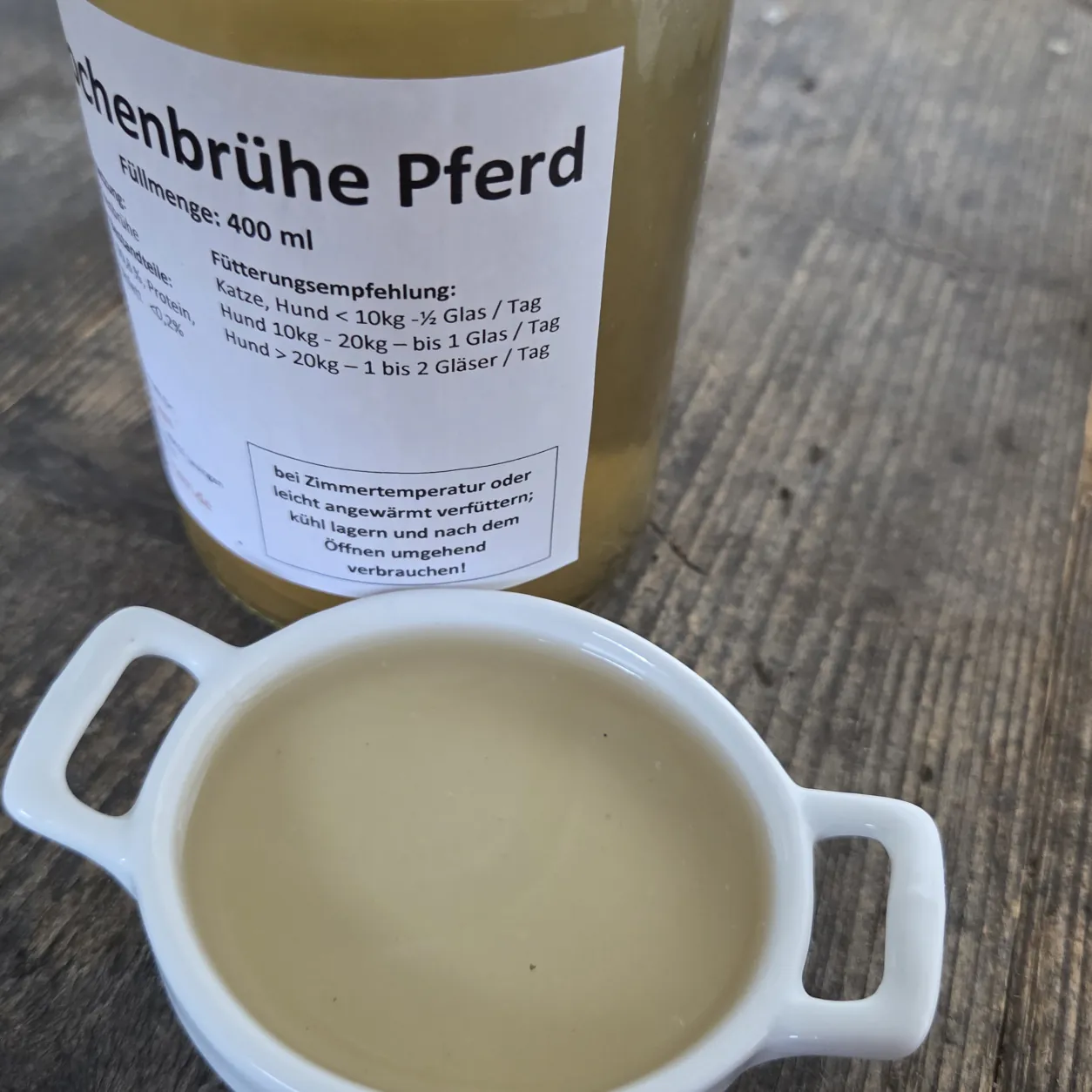 Knochenbrühe Pferd in einer Schüssel mit dem Produktglas von funem im Hintergrund