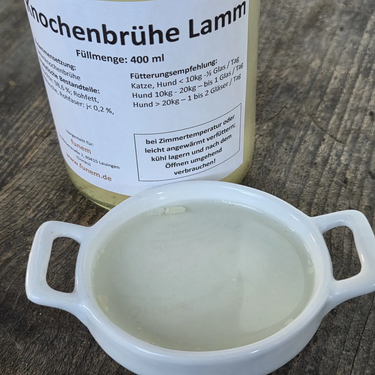 Knochenbrühe Lamm in einer Schüssel mit dem Produktglas von funem im Hintergrund