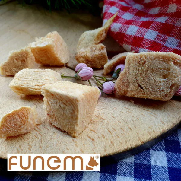 Gefriergetrocknete Leckerlis für Hunde von funem – natürliche Fleischstücke auf Holzbrett mit rot-weißem Tuch