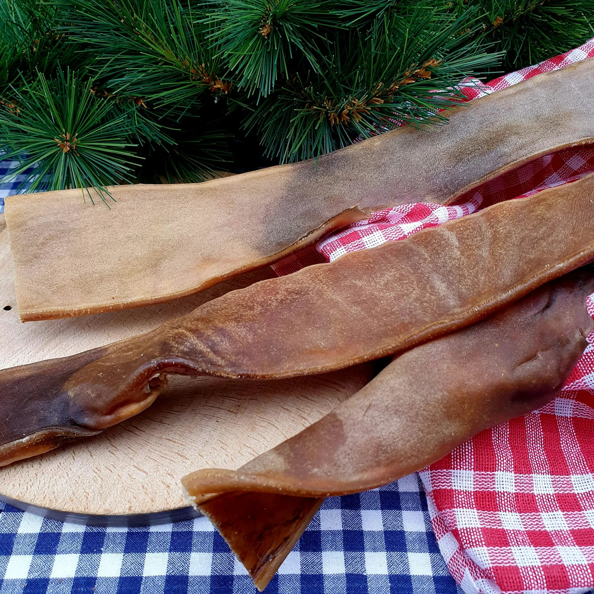 Kamelhaut – fester Naturkauartikel für Hunde Kamelhaut – fester, zäher Naturkauartikel für Hunde, auf Holzbrett fotografiert.